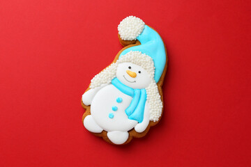 Tasty Christmas cookie in shape of snowman on red background, top view