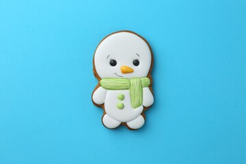 Tasty Christmas cookie in shape of snowman on light blue background, top view