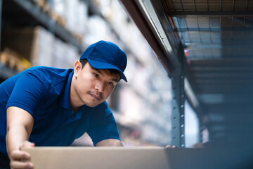 A man in a blue shirt is looking at a box. He is wearing a blue hat