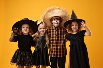 Cute children wearing Halloween costumes on orange background