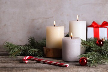 Burning candles, Christmas decor and fir tree branches on wooden table, closeup