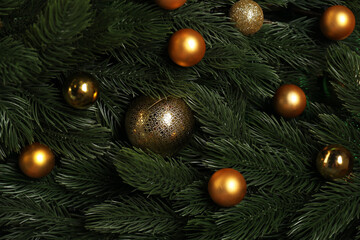 Fir tree branches and shiny Christmas baubles as background, top view