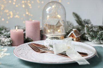 Christmas place setting with plate, cutlery and festive decor on table, closeup