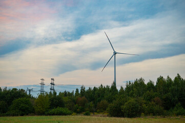 Landscape with Wind Turbines and electricity transmission lines on a field in autumn, Berlin, Germany. Green power generation. Windmills for electric power production at sunset. 