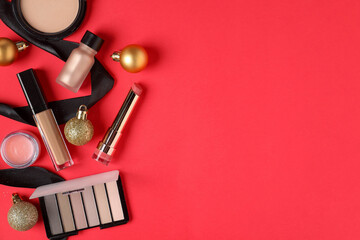 Flat lay composition with makeup products and Christmas decor on red background, space for text