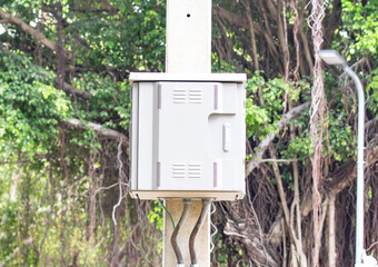 Internet signal box attached to concrete power pole on natural tree background. Universal inverter...