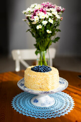 Homemade birthday cake called Apfelmus decorated with blueberries on porcelain plate on blue lace napkin