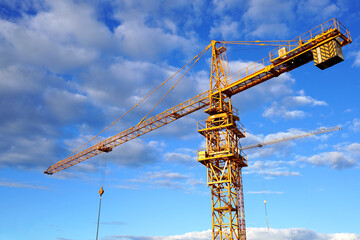 Construction crane on on blue sky background. Tower Crane on building construction. Multi Storey Residential Building under construction. Tower Crane close up.