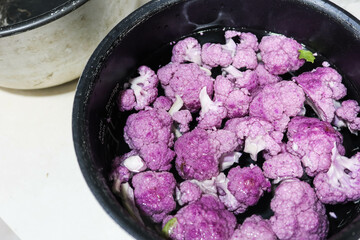 close up of purple cauliflower being washed and floating in a bowl of water ready for cooking