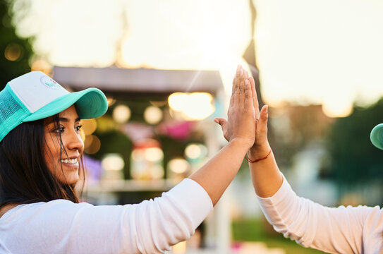 Woman, smile and outdoor for high five for success, win and achievement in community service. Volunteer, team and hand gesture at function for celebration, good job or positive for NGO drive at event