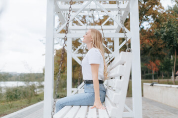 Middle-Aged Blonde Woman Enjoying a Peaceful Moment on a Swing in Nature