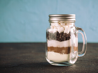 Hot chocolate mix in mason jar. Homemade mix from cocoa, dry milk, sugar, chocolate chips and marshmallows. Christmas and winter holiday budget-friendly holiday gifts idea. Copy space. Toned image