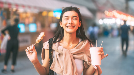 Happy asian foodie woman eating street food holding korea skewer oden