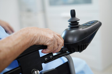 Asian elderly disability woman patient use joystick electric wheelchair in hospital.