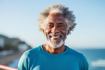 Portrait of a cheerful afro-american elderly man in his 90s sporting a breathable mesh jersey while standing against serene seaside background
