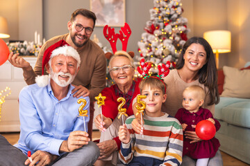 Family celebrating New Year at home holding balloons shaped as numbers 2025