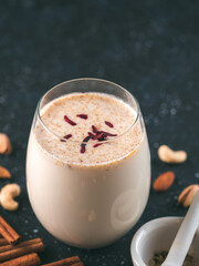 Thandai or Sardai cold drink made during Holi festival. Cold milk drink in glass, with ingredients - nuts and spices. Copy space