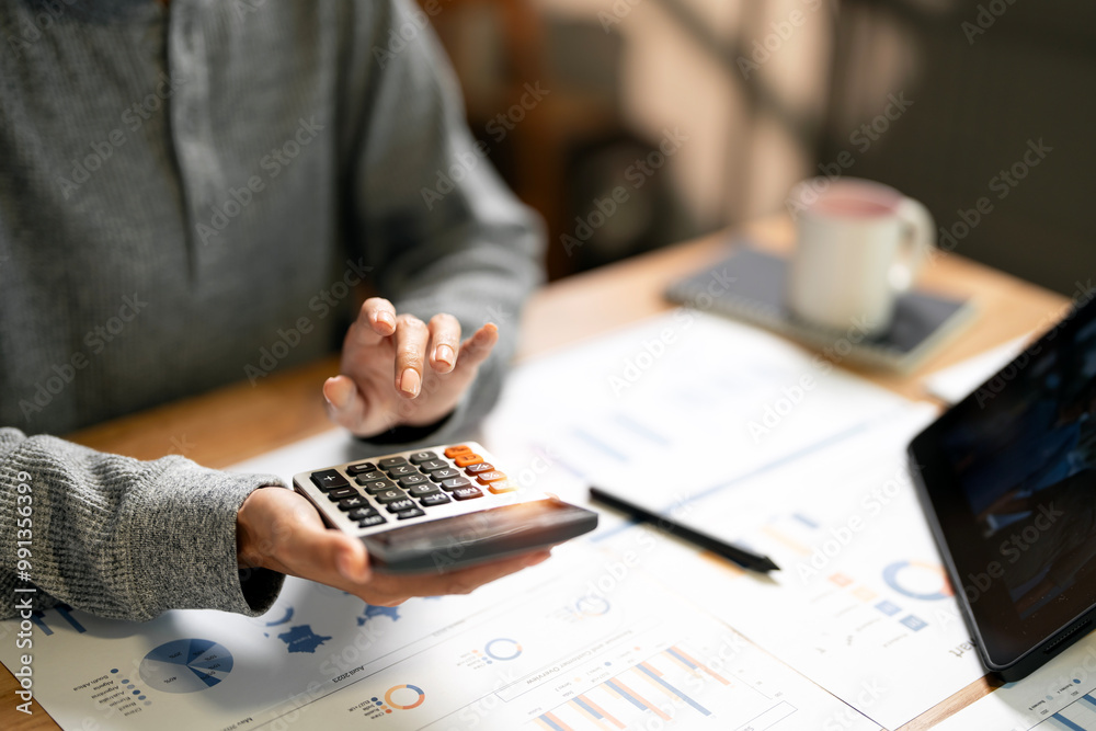 Wall mural close up woman hand using calculator. doing finance, budgeting and tax calculation, monthly expenses