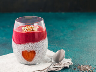 Idea for healthy breakfast on Valentine's Day: Chia pudding with red berry puree, chopped almonds on top and strawberry in the shape of heart. Copy space for text