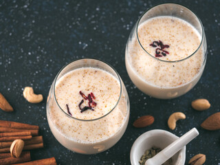 Thandai or Sardai cold drink made during Holi festival. Cold milk drink in glass, with ingredients - nuts and spices. Copy space