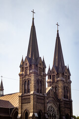 Obraz premium City building landscape, Gothic church towers and spiers, arched windows of a stone building. Color vertical photo from the side of the church facade.