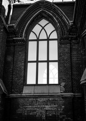 Building cityscape, gothic church architecture, with arched glass windows, christian religion and culture. Black and white vertical photo from bottom to top.
