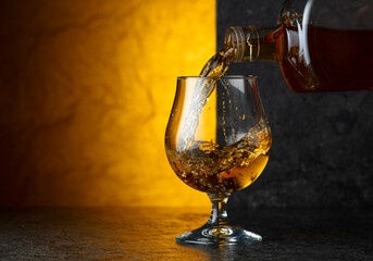 Pouring brandy from a bottle into a glass.