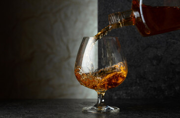 Pouring brandy from a bottle into a glass.