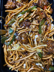 Close up top view of chilli garlic Manchurian noodles served in a sleek black rectangular box.