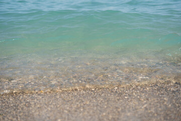 Sea view. Calm blue ocean wave and pebbles beach background. Relax, vacations, tranquility. Copy space for text, soft focus