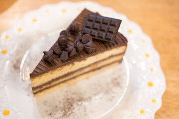 Delicious triangle shape slices piece of dark chocolate fudge cake topping with chocolate