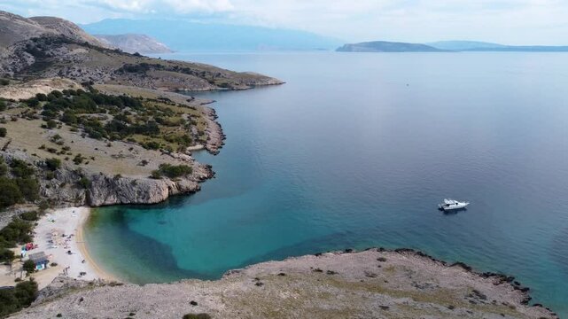 Slow Forward Drone View of Turquoise Cove, Pebble Beach and Motor Yacht in Stara Ba&scaron;ka, Krk Island, Croatia