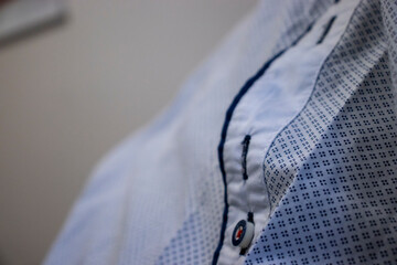 Close-up of a blue and white checkered shirt with detailed stitching and buttons, emphasizing...