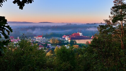 View of Zelív illuminated by the morning sun, foggy, monastery