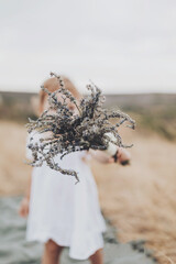 little girl with lavender bouquet in her hand in the field. Girl hid her face behind bouquet of dry lavender. Walk in countryside.