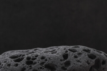 Porous stone podium on black background. Product display, jewelry, technology background. Natural...