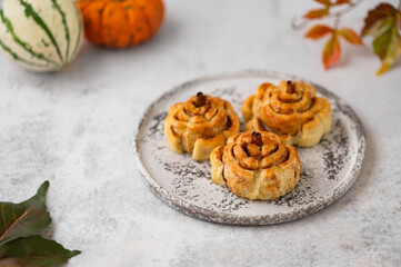 Pumpkin cinnamon rolls. Fresh homemade Cinnamon Rolls in the form of pumpkins. Bakery for Halloween or Thanksgiving party. Cozy autumn, winter still life with pumpkins.