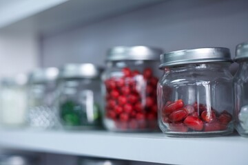 glass jars with candies tablets or beads inside. jars with bright circles on the shelf are arranged in a row. High quality photo