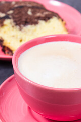 Cup of coffee with milk and fresh baked yeast dough with cocoa and chocolate icing. Delicious dessert