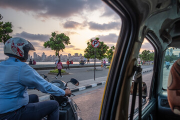 A man rides a scooter down the bay in the City as seen from the back of a car © Chris
