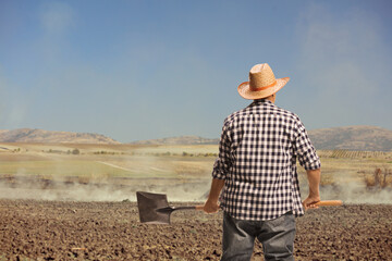 Rear view shot of a farmer with a shovel standing on a field