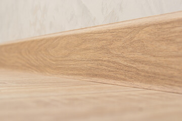 Plastic skirting board with wood texture. Wide floor skirting board. Soft focus