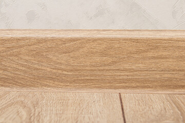 Plastic skirting board with wood texture. Wide floor skirting board closeup