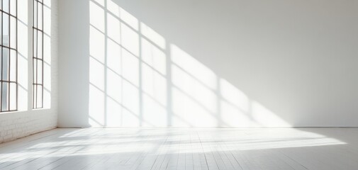 Fototapeta premium Spacious interior with wooden floor and large windows casting soft shadows across the white walls, creating a serene and peaceful atmosphere for various uses.