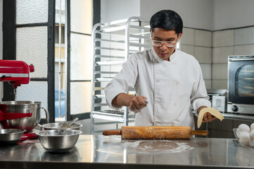 The baker places flour on a rolling pin to make the process easier.