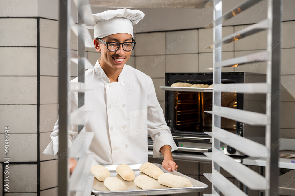 Wall mural pastry chef places the processed bread on an aluminum shelf.