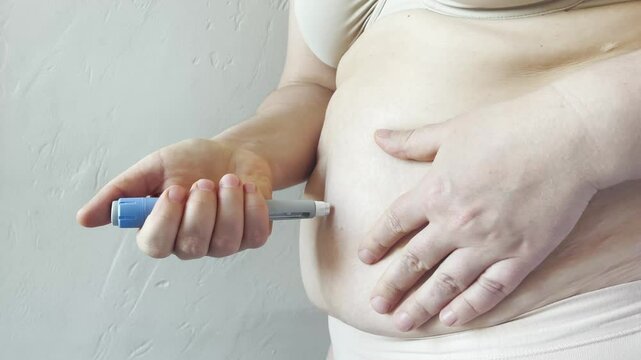 Woman making Semaglutide Injection closeup. Semaglutide or insulin Injection pen in female belly. Semaglutide Diabetes Drug Being Used For Weight Loss.