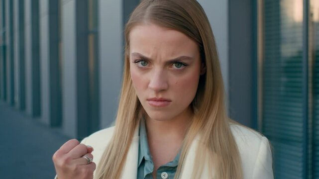 Aggressive Caucasian woman annoyed businesswoman female worker furious executive demonstrating fist in camera anger business girl manager work harder warning gesture threat displeasure in city urban