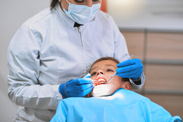 Checkup, dentist and examination with child in hospital for procedure or consultation in oral care clinic. People, patient and protective mask as hygienist for teeth cleaning or root canal treatment