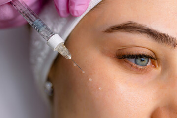 Beautiful relaxed woman at beautician cabinet receiving anti wrinkle injections on cheekbones, lying with closed eyes in beauty salon